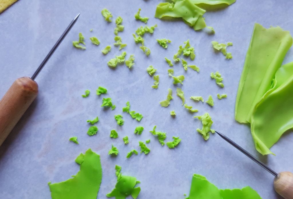Étape de création d'un charm en fimo en forme de kébab miniature ou sandwich grec : découper les feuilles de salade.